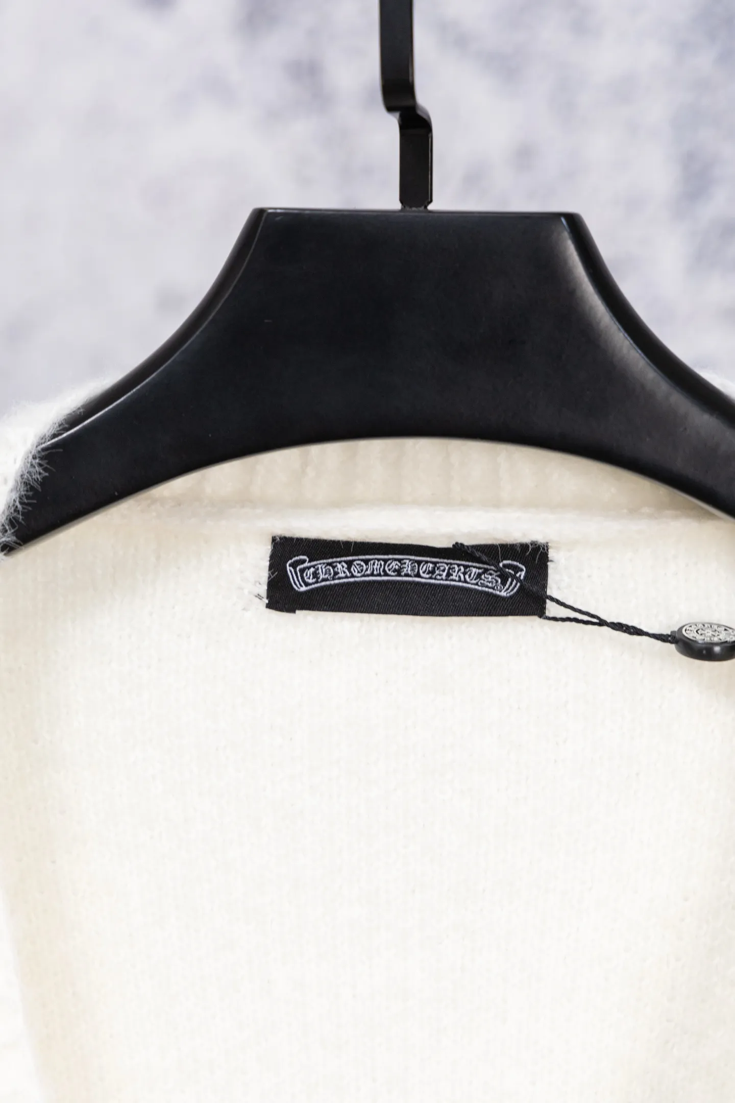 P300 Chrome Hearts CH Chrome Hearts 2026 new cross loose knitted V-neck cardigan Fabric: Made of plush textured knitted material, soft to the touch and with a lazy atmosphere; Decoration: Red, yellow, and black cross ornaments on the chest, paired with brand logo patches, which are iconic elements of street fashion brands (such as Chrome Hearts style), enhancing visual recognition; Version: Loose version + single-row metal button design, combining casual feeling and practicality. 2. Style and Adaptation Style: It combines dark street style and gentle knitted texture, which belongs to the tone of "sweet and cool mix"; Scenario: Can be worn with a T-shirt/suspender to create a daily street look, or can be layered with a shirt for light casual wear. Color: Black White Size: M L XL